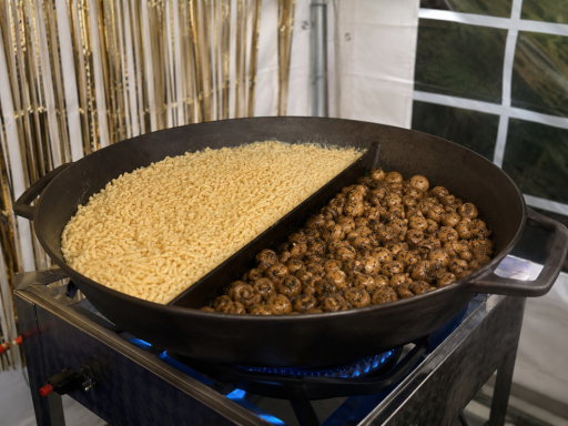 Gusspfanne Eine große Pfanne mit hellem und dunklem Essen, auf einem Herd gekocht.